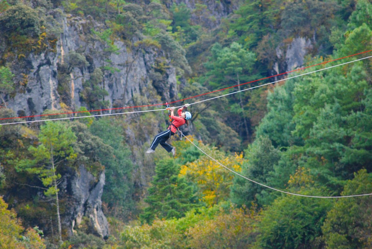 A student crossing a Tyrolean traverse above the jungle on an APA school program